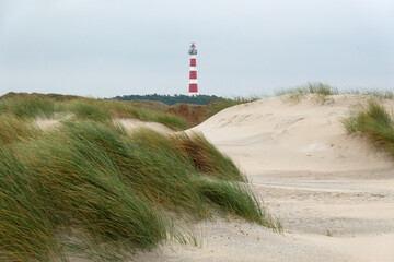 View over the dunes on the red and white lighthouse of the Dutch island Ameland