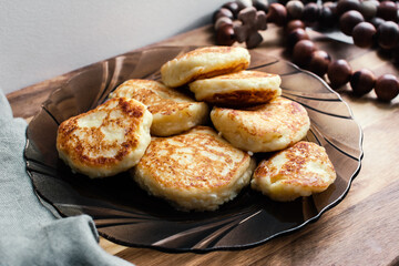 Vanilla cottage cheese pancakes ( syrniki or curd fritters) on a plate in winter morning. High-protein breakfast ideas.