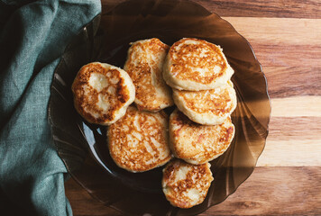 Vanilla cottage cheese pancakes ( syrniki or curd fritters) on a plate in winter morning. High-protein breakfast ideas. Top view.