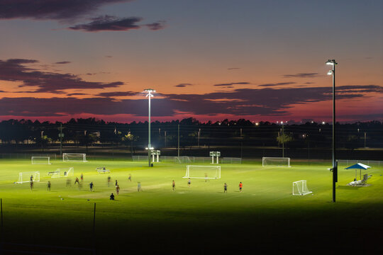 Public sports stadium with young people playing football game at sunset. Active way of life concept - Powered by Adobe