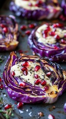 Close-up of roasted cabbage slices topped with pomegranate seeds and cashew cream on a gray baking sheet