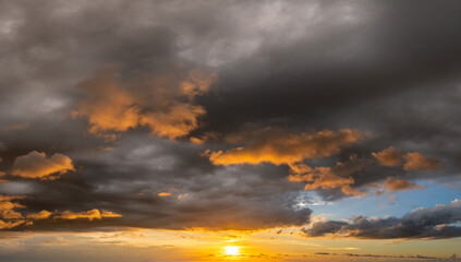 Sunset sky with bright colorful orange and yellow clouds. Panoramic skyscape