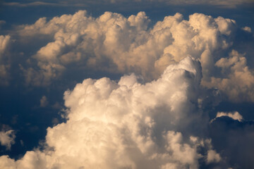 View from plane window of white rain clouds forming on blue sky. Air travel concept