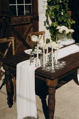Minimalist holiday decor with white flowers and candles, outdoors.