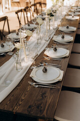 A wooden table with wooden chairs. White carpet, white dishes with gold patterns.