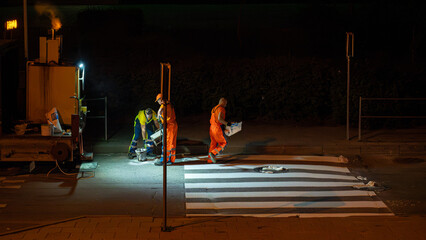 Nighttime Roadwork in the City: Workers and Machinery Repairing Urban Roads Under Artificial Light