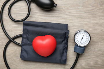 Blood pressure measuring device and squeeze heart on wooden table, top view