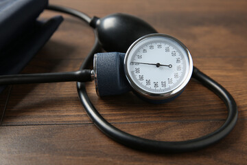 Blood pressure measuring device on wooden table, closeup