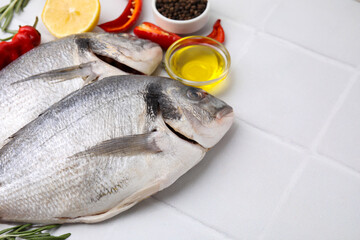 Sea food. Fresh raw fish and products on white tiled table, closeup. Space for text
