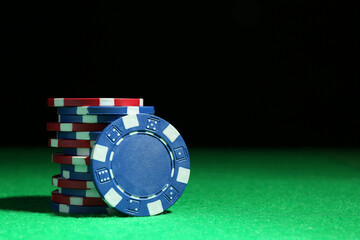 Naklejka premium Poker chips on green table against dark background, closeup. Space for text
