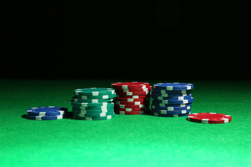 Poker chips on green table against dark background