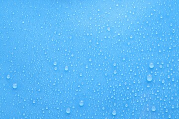 Water drops on light blue background, top view