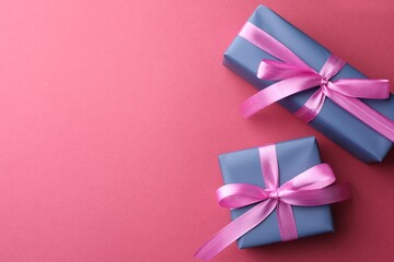 Beautiful gift boxes with bows on pink background, top view. Space for text