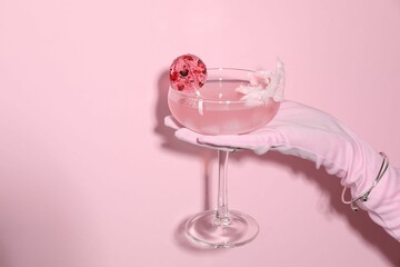 Woman holding glass of drink on pink background, closeup. Space for text