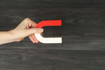 Woman with horseshoe magnet on wooden background, closeup