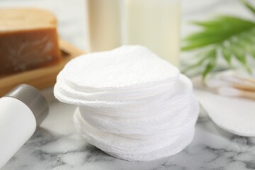 Cotton pads and cosmetic products on light marble table, closeup
