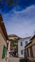 Fototapeta premium The narrow street of the small Tuscan town with a view of the mountain and blue sky. Pomonte, Elba, Italy