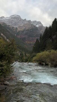 R&iacute;o en un paisaje oto&ntilde;al con monta&ntilde;as nevadas bajo un cielo nublado en el Parque Nacional de Ordesa