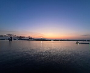 Obraz premium Sunset on the Mississippi River with tug boat and golden glowing clouds on the blue sky in Baton Rouge, Louisiana, USA