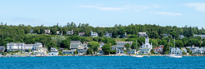 skyline of mackinac island with white houses and a white church on lake huron