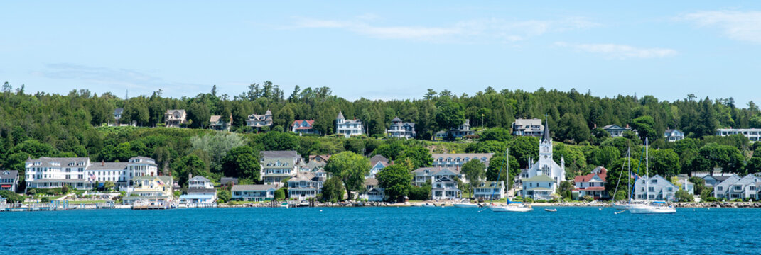 skyline of mackinac island with white houses and a white church on lake huron