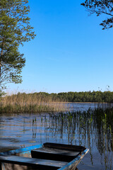 A blue wooden boat moored on the shore of a lake, Borki, Warmian-Masurian Voivodeship, Poland