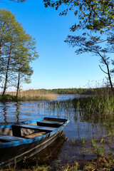 A blue wooden boat moored on the shore of a lake, Borki, Warmian-Masurian Voivodeship, Poland