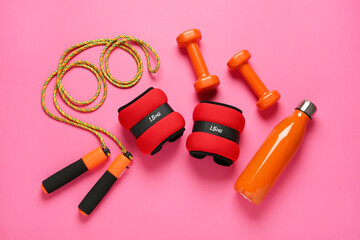 Red ankle weights and sport equipment on pink background, flat lay
