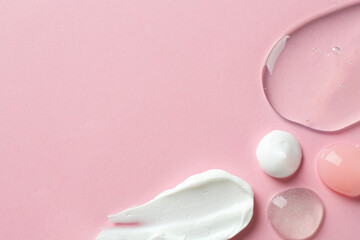 Smears of different cosmetic products on pink background, flat lay. Space for text