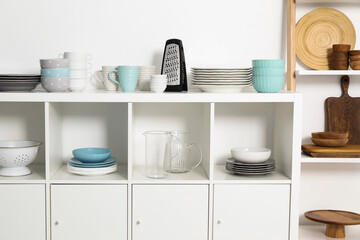 Storage cabinet with kitchenware near white wall indoors