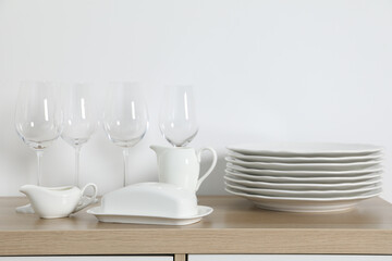 Tableware on wooden storage cabinet near white wall indoors