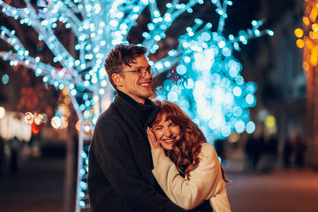 Loving festive couple hugging on street on christmas and new year's eve