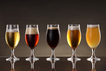 Glasses with different types of beer on mirror surface