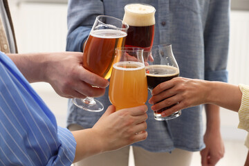People with different types of beer clinking glasses, closeup