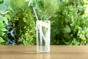 Glass of soda water with lime on wooden table against blurred background