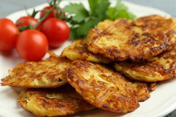 Delicious potato pancakes, tomatoes and parsley on plate, closeup