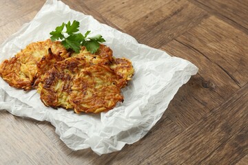 Delicious potato pancakes and parsley on wooden table, closeup