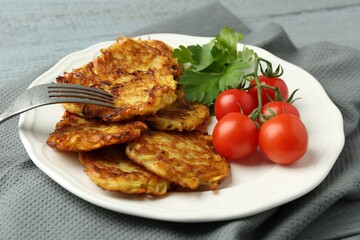 Delicious potato pancakes with tomatoes and parsley served on gray table, closeup