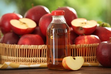Tasty apple juice in glass bottle and fresh fruits on wooden table outdoors