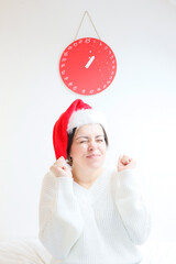 The girl is waiting for Christmas, in a Santa hat against the background of a red advent calendar
