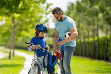 Happy family. Father helping son get ready for school. Child in safety helmet with father riding bike in summer day. Fatherhood. Support parent. Fathers day. Child care.