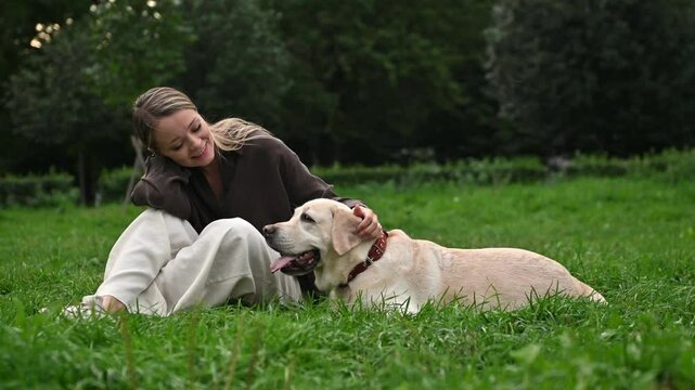 
A blonde girl is playing on a walk with her dog. A Labrador and a girl are having fun on vacation. A dog trainer is engaged with Labradors in the park
