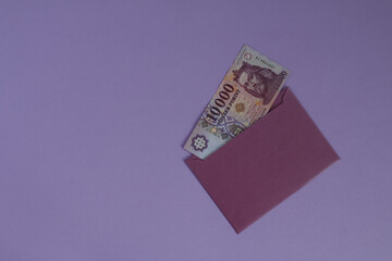 A Hungarian banknote is visible in the envelope. It is in a purple envelope on a purple background.