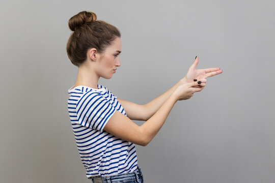Side view of assertive dangerous woman pointing fingers at target imitating weapon making shot.