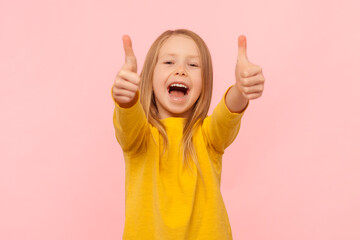 Excited smiling happy blonde little girl showing ok sign, like gesture, laughing, being in good mood