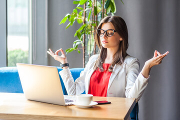 Woman working on laptop long hours trying to relax practicing yoga to calm down meditating.