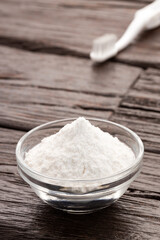 Baking soda in bowl and toothbrush - Wooden background.