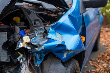 heavily damaged car with crumpled hood and exposed engine, aftermath collision, crash scene, with...