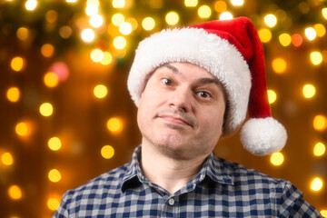 A man face, poses in New Year decorations with festive illumination and garlands, Christmas lights and decorations background, Holiday theme