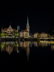 Naklejka premium Beautiful aerial view of the city of Zurich in Switzerland at night - the Limmat River and its iconic churches, buildings rivers and Clocks.